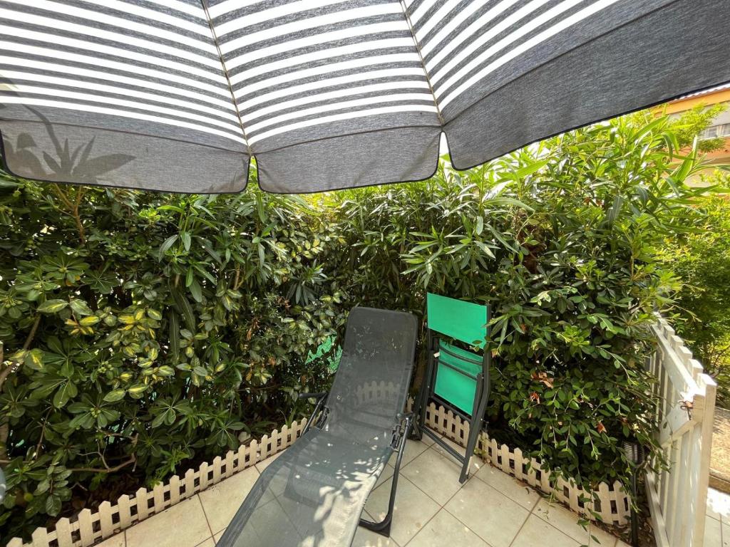 une terrasse avec une chaise et un parasol dans l'établissement A la grande conque, au Cap d'Agde