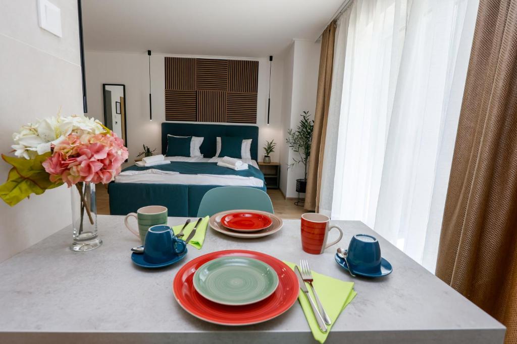 a room with a bed and a table with plates at Várvavár Apartman Gyula in Gyula
