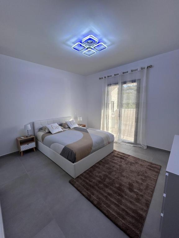 une chambre blanche avec un grand lit et une fenêtre dans l'établissement Bel Appartement F3 proche de la plage, à Pietrosella