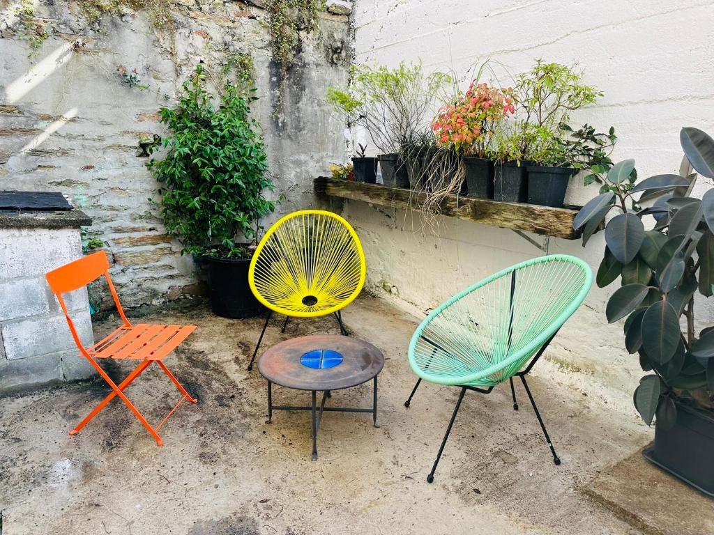 3 chaises colorées et une table dans la cour dans l'établissement Location maison de vacances Concarneau - 4 personnes, à Concarneau