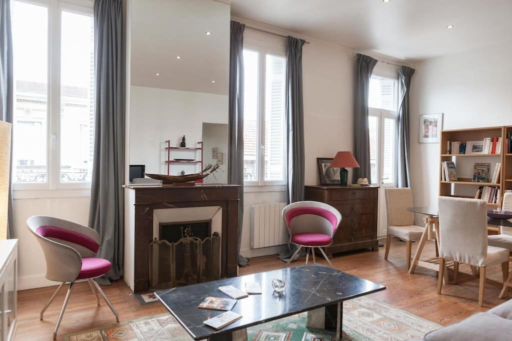 - un salon avec une cheminée et des chaises roses dans l'établissement Appartment 80m2 in Saint Michel for 6 persons, à Bordeaux