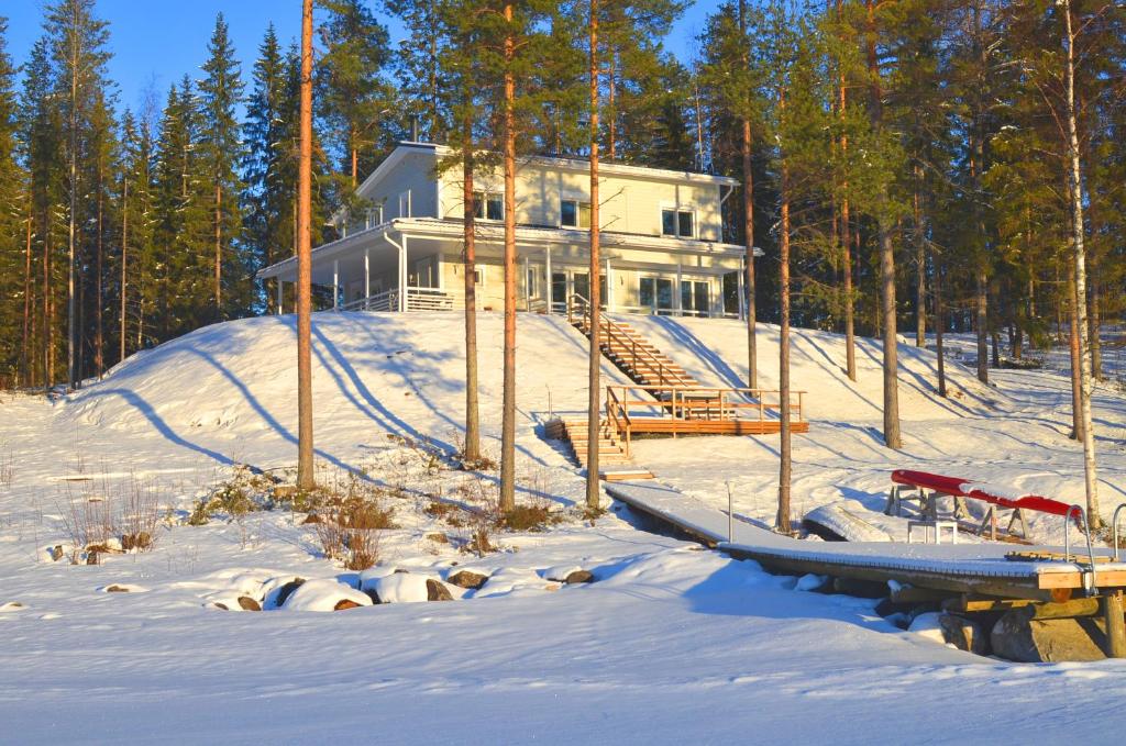 une maison dans la neige avec un bateau devant elle dans l'établissement Kainiemen Huvilat, à Nurmes