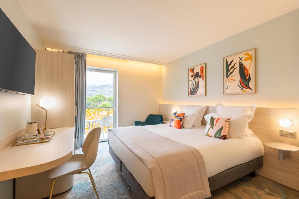 une chambre d'hôtel avec un lit, un bureau et une fenêtre dans l'établissement Ilot du Golf BW Premier Collection, à Mandelieu-la-Napoule