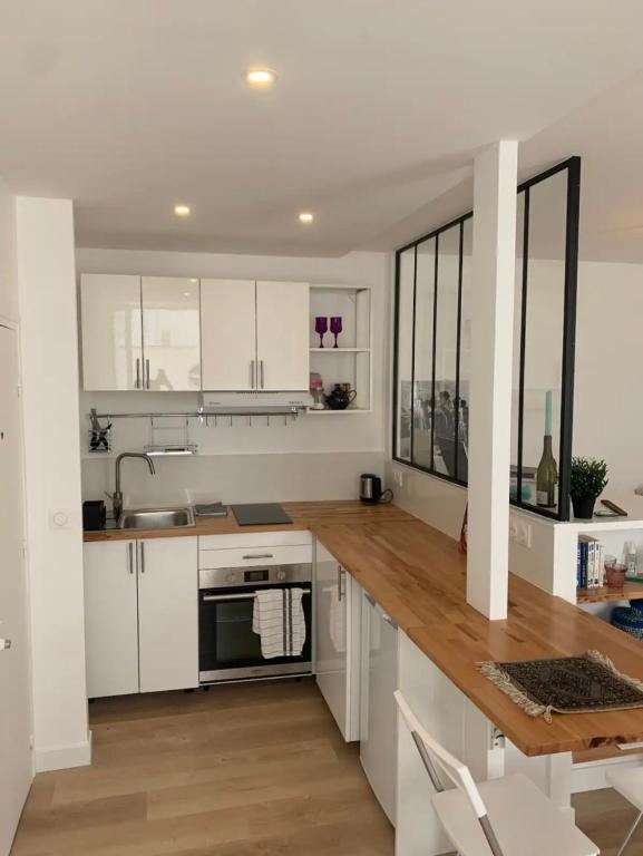 une cuisine avec des armoires blanches et un plancher en bois dans l'établissement Lovely appartement in Montmartre, à Paris