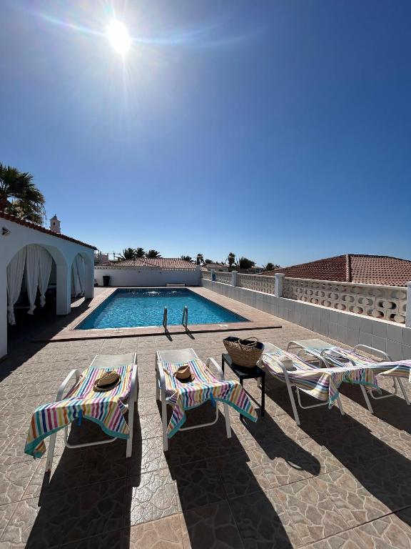 ein Swimmingpool mit Stühlen und ein paar Leuten in der Unterkunft Villa Sole# Luxury Amarilla Golf in San Miguel de Abona