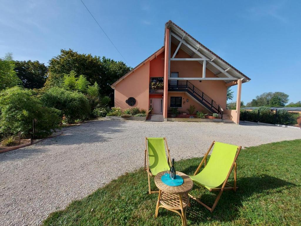 two chairs and a table in front of a house at Aux couleurs du lac in Géraudot