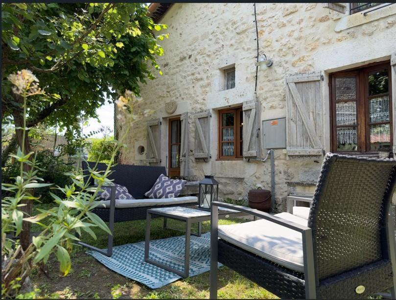 patio z krzesłami i stołem przed budynkiem w obiekcie Chez l'antoinette w mieście Persac