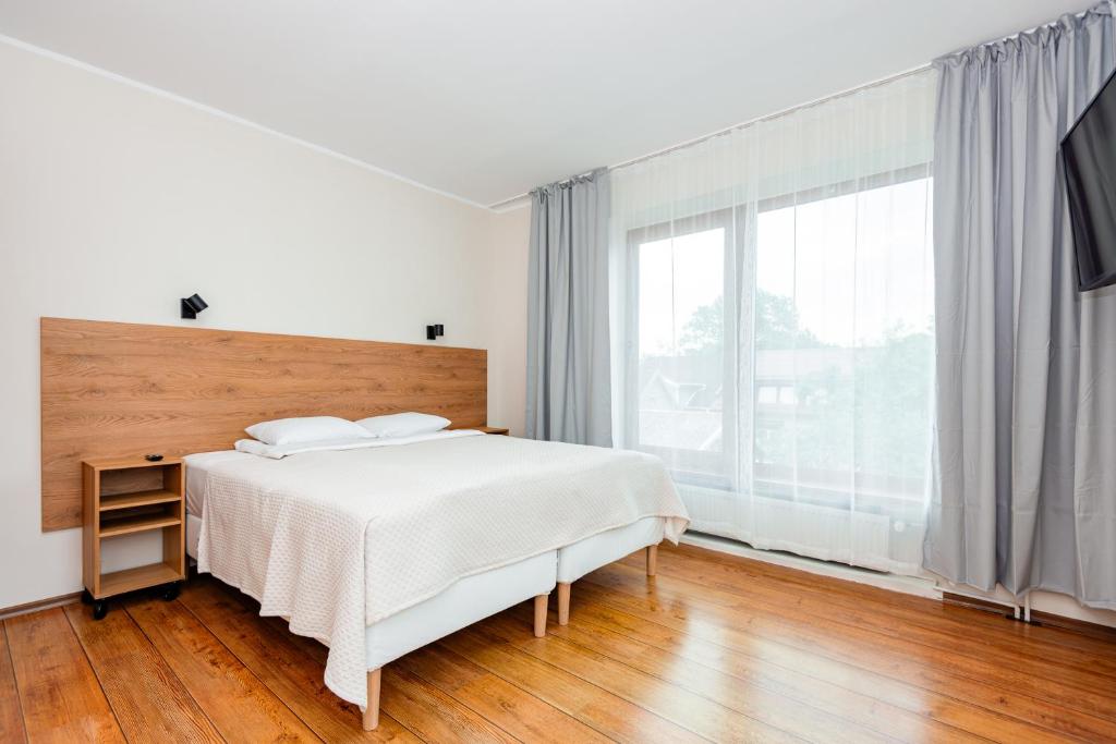 a white bedroom with a bed and a large window at Smilciu 34 in Palanga