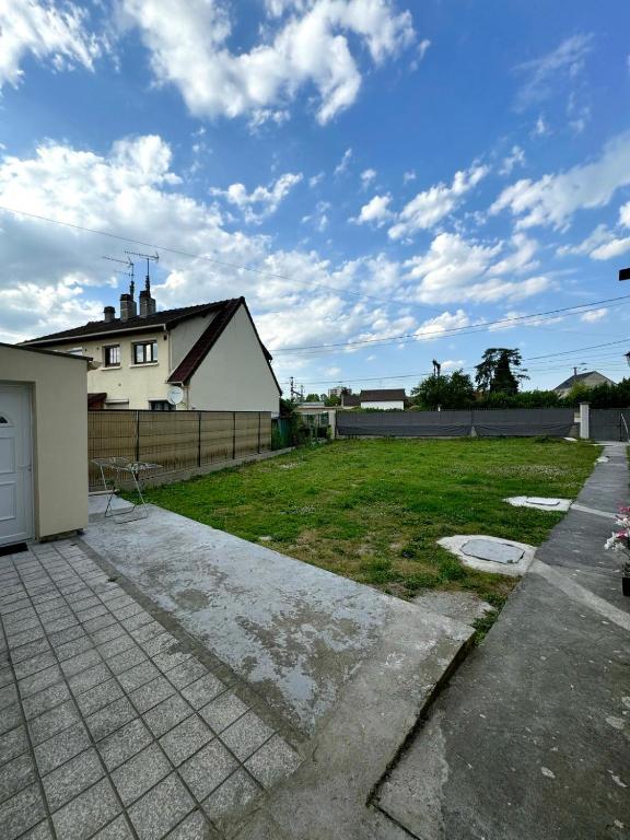 une cour avec une maison et un champ d'herbe dans l'établissement Bonheur, à Sevran
