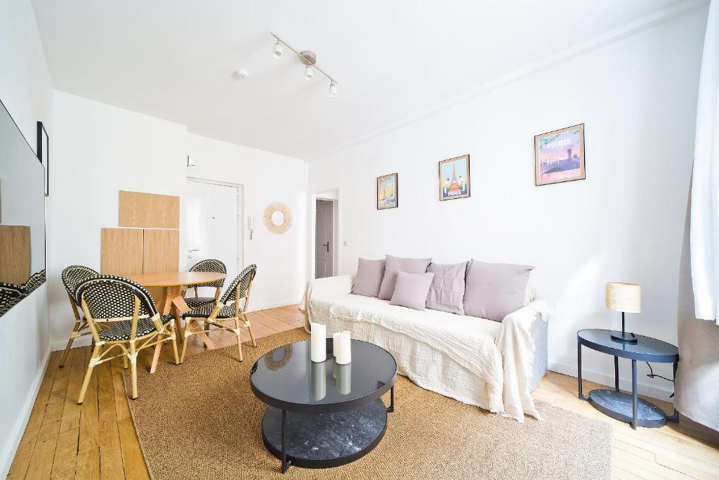 ein Wohnzimmer mit einer weißen Couch und einem Tisch in der Unterkunft Magnifique appartement parisien in Paris