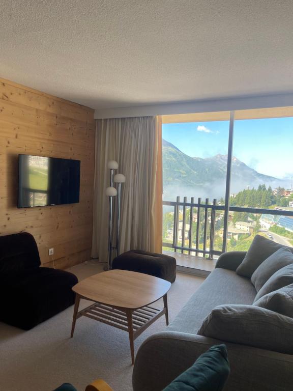 un salon avec un canapé et une grande fenêtre dans l'établissement Vallonpierre, à Orcières