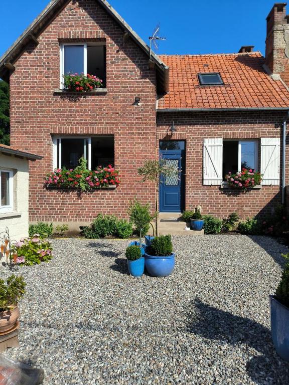 une maison en briques avec des plantes en pot devant elle dans l'établissement Chez Bruno, à Senarpont