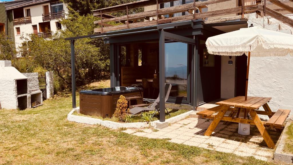 dom ze stołem piknikowym i parasolem w obiekcie Can Sansa Appartement 4* jacuzzi maison pyrénéenne w mieście Font-Romeu-Odeillo-Via