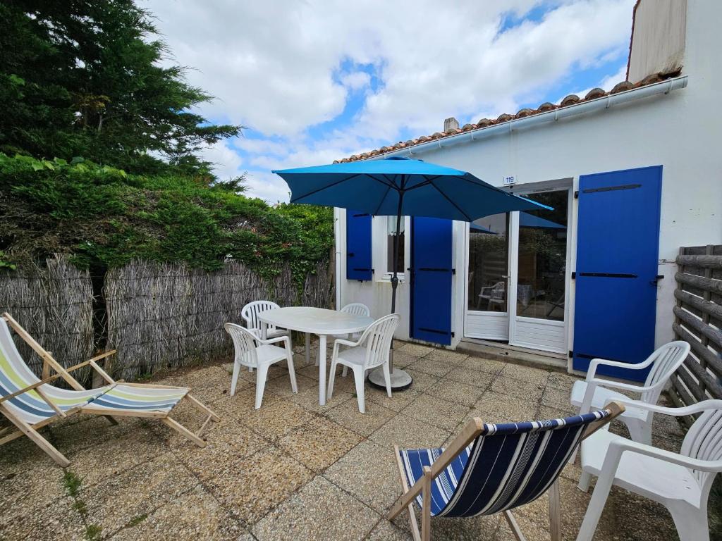 a patio with a table and chairs and an umbrella at Maisonnette à 150m de la plage, parking privé - FR-1-476-8 in La Faute-sur-Mer