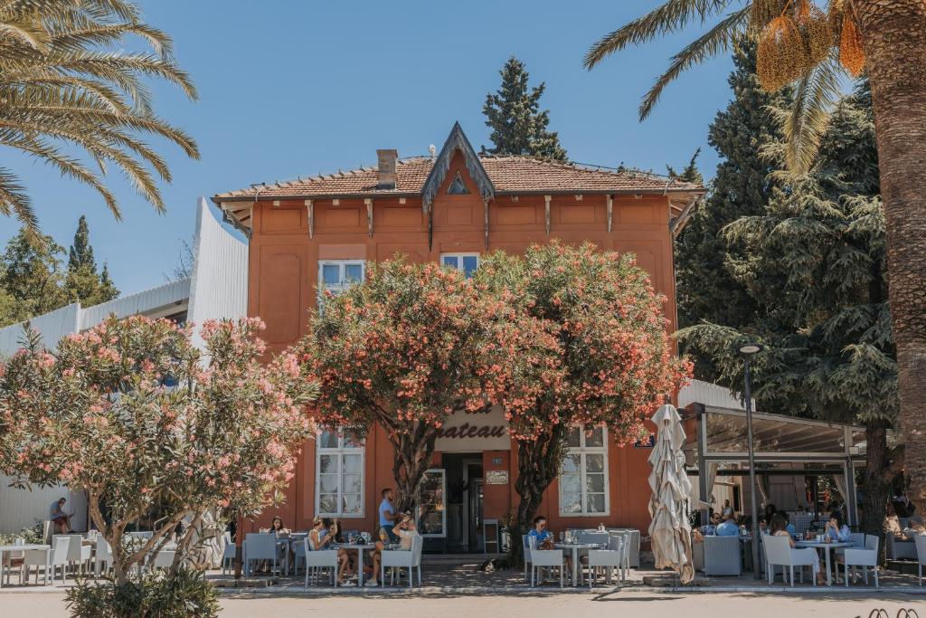 a building with tables and trees in front of it at Le Petit Chateau in Bar