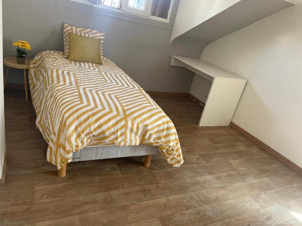 un letto con un piumone e un tavolo in una stanza di Chambre avec balcon dans charmante maison prêt d' aéroport d'Orly et proche paris a Villeneuve-le-Roi