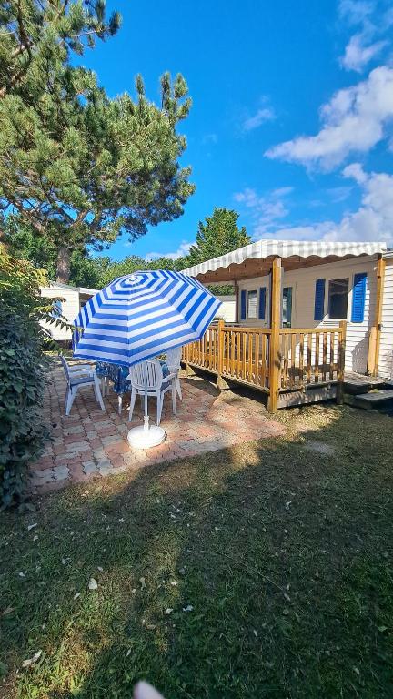 a patio with a blue and white umbrella and benches at Bungalow bord de mer in Les Mathes