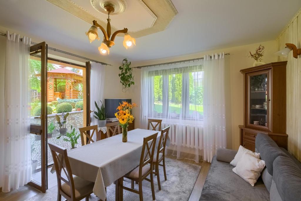 a dining room with a table and chairs and a couch at Apartament U Jagody in Tylicz