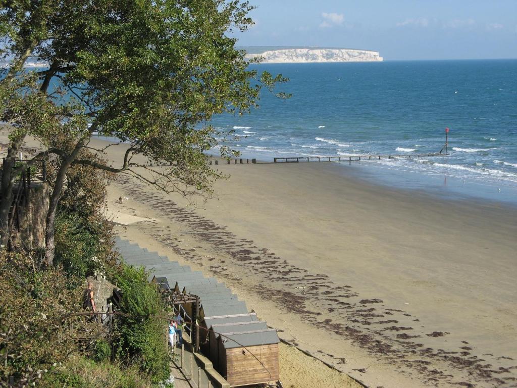 Una playa con gente caminando sobre la arena y el océano. en Gurnard At The Aqua, en Shanklin