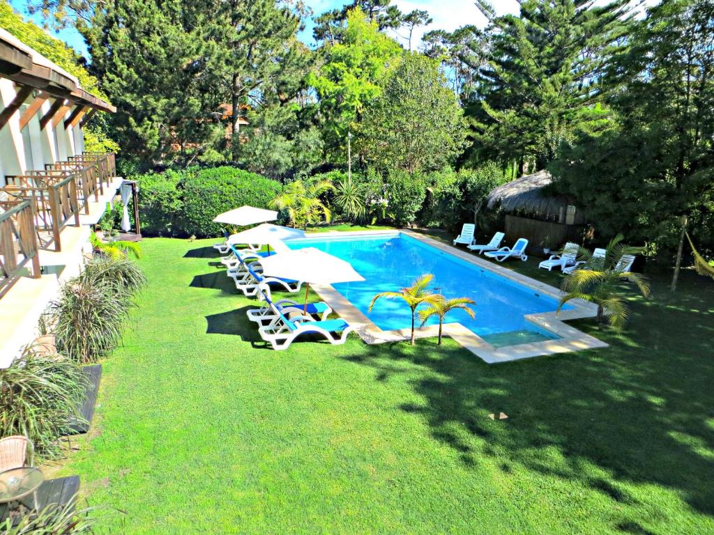 a swimming pool with chairs and umbrellas next to a yard at Petit Chateau Hotel Boutique in Punta del Este