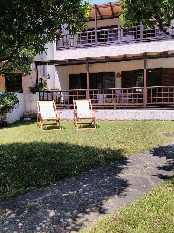 two chairs sitting in the grass in front of a building at Orsiida Seaside Cottage KGatzea in Kato Gatzea