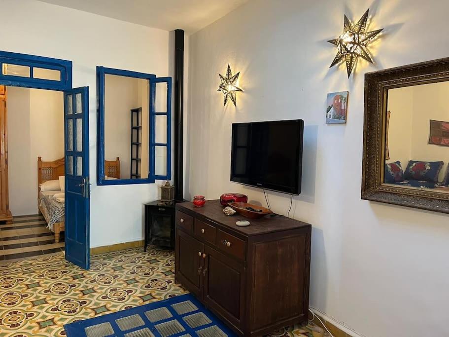 a living room with a tv and a dresser and a mirror at Casa María in Asilah