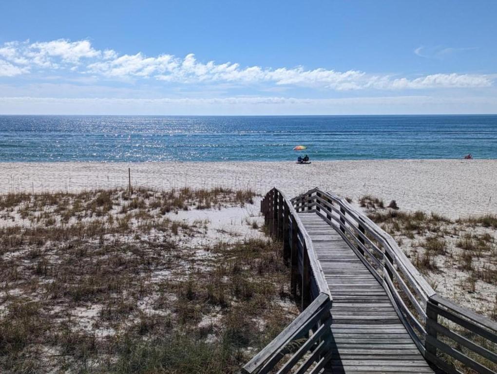 a wooden boardwalk to the beach with an umbrella at Gulf Side Villa 1B in Pensacola