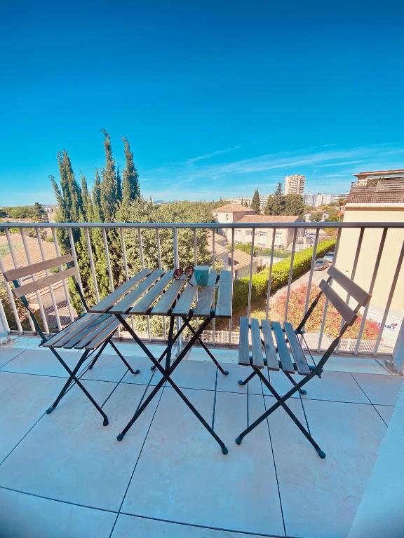 une table de pique-nique et deux chaises sur un balcon dans l'établissement Le Belvédère - Studio avec vue YourHostHelper, à Montpellier