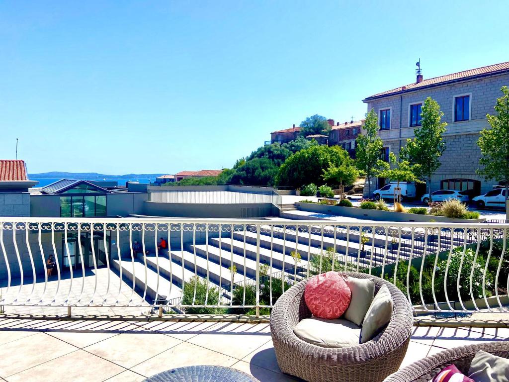 d'un fauteuil en rotin avec des oreillers sur le balcon. dans l'établissement Casa Porti Vechju, à Porto-Vecchio