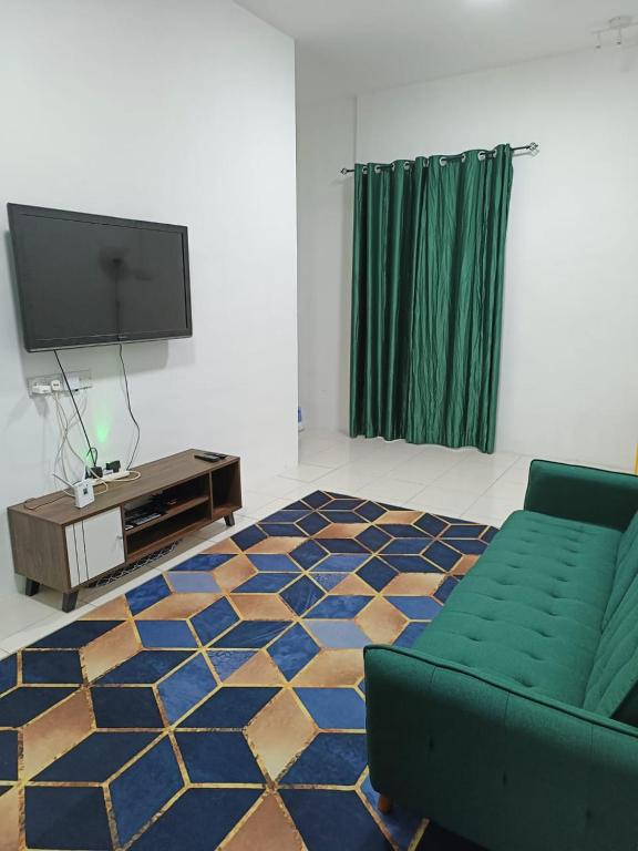 a living room with a couch and a flat screen tv at Rumah SK in Batu Kurau