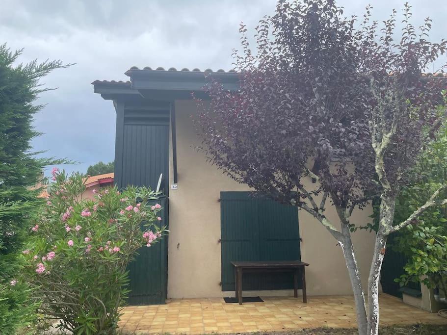 une maison avec une porte verte et un banc dans l'établissement Maison avec jardin- à 3' du lac, à Hourtin