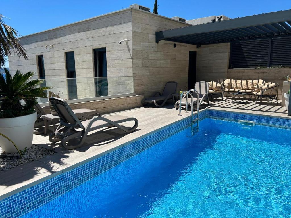 a swimming pool with chairs next to a house at BEACH FRONT VILLA FRAN - DELUXE PENTHOUSE SUITE with private pool in Crikvenica