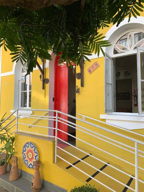 a yellow house with a red door at Hostel Casarão in Viçosa