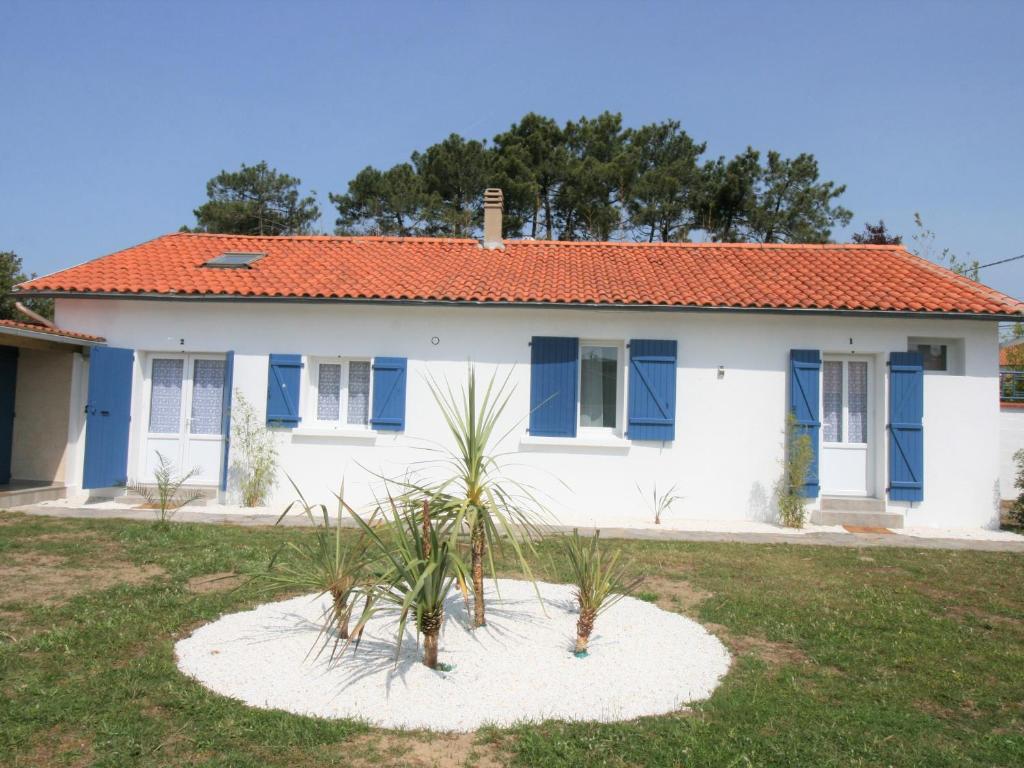 une maison avec des volets bleus et des plantes dans la cour dans l'établissement Charmant logement rénové 2/3 pers, jardin commun, 750m plage, 850m centre-ville - FR-1-22-350, à La Tranche-sur-Mer