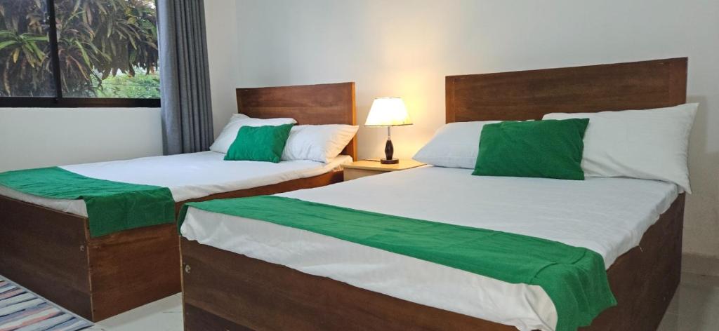 two beds in a hotel room with green sheets at Hills Kandy Apartment in Kandy
