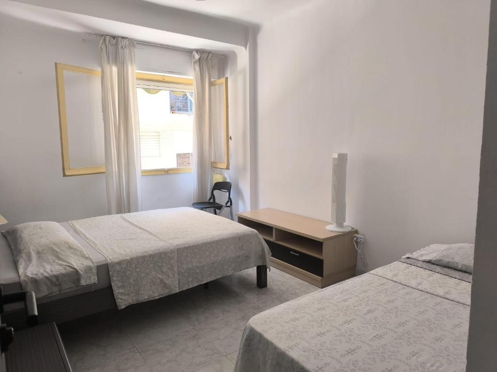ein Schlafzimmer mit zwei Betten und einem Tisch und einem Fenster in der Unterkunft Alicante Habitación Oasis in Alicante