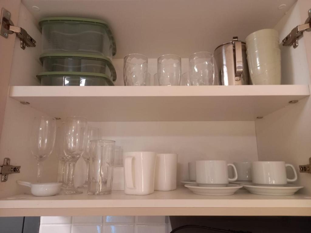 a shelf with glasses and cups and plates on it at Lindo Apartamento no Centro de Porto de Galinhas in Porto De Galinhas