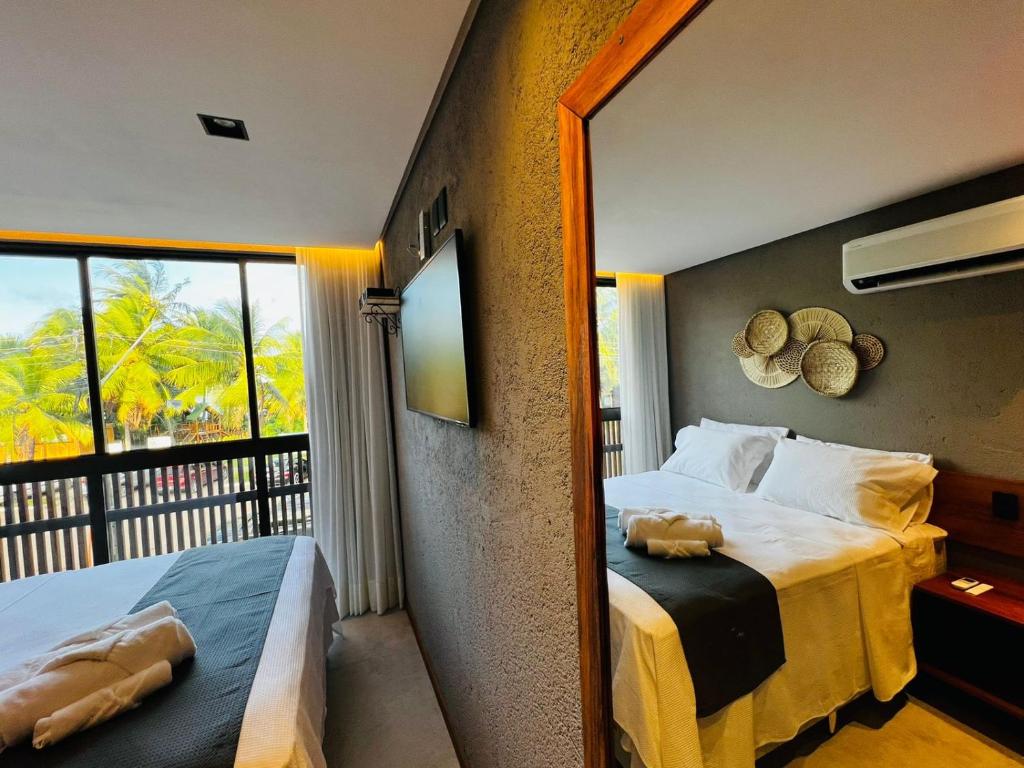 a bedroom with a large bed and a mirror at Villa Mutum - Triplex na Rota Ecológica dos Milagres Praia do Patacho in Pôrto de Pedras