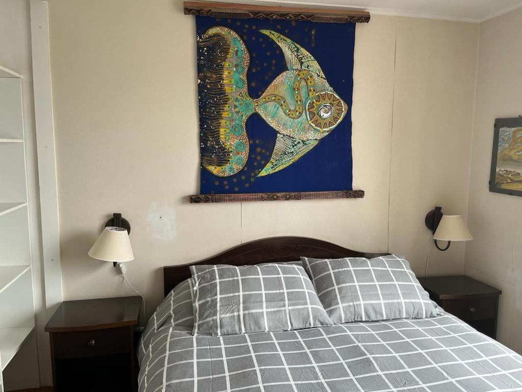 a bedroom with a bed and a painting on the wall at Horcon Condominio CAUCAU in Horcón
