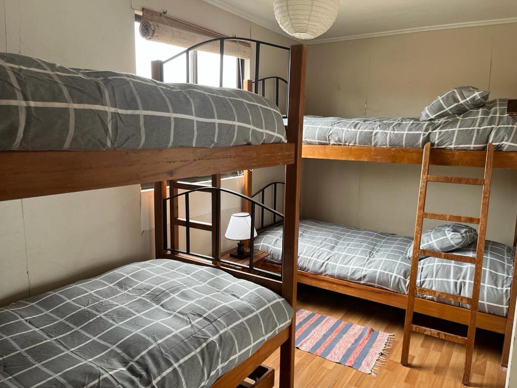 two bunk beds in a room with a bed and a chair at Horcon Condominio CAUCAU in Horcón