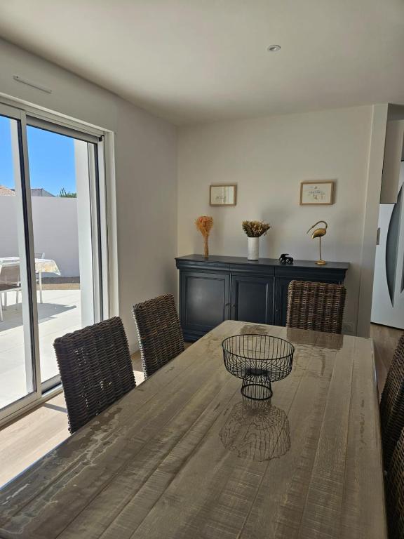 une salle à manger avec une table et des chaises en bois dans l'établissement MAISON de Vacances Entière à 10 mn de La Rochelle, à Dompierre-sur-Mer