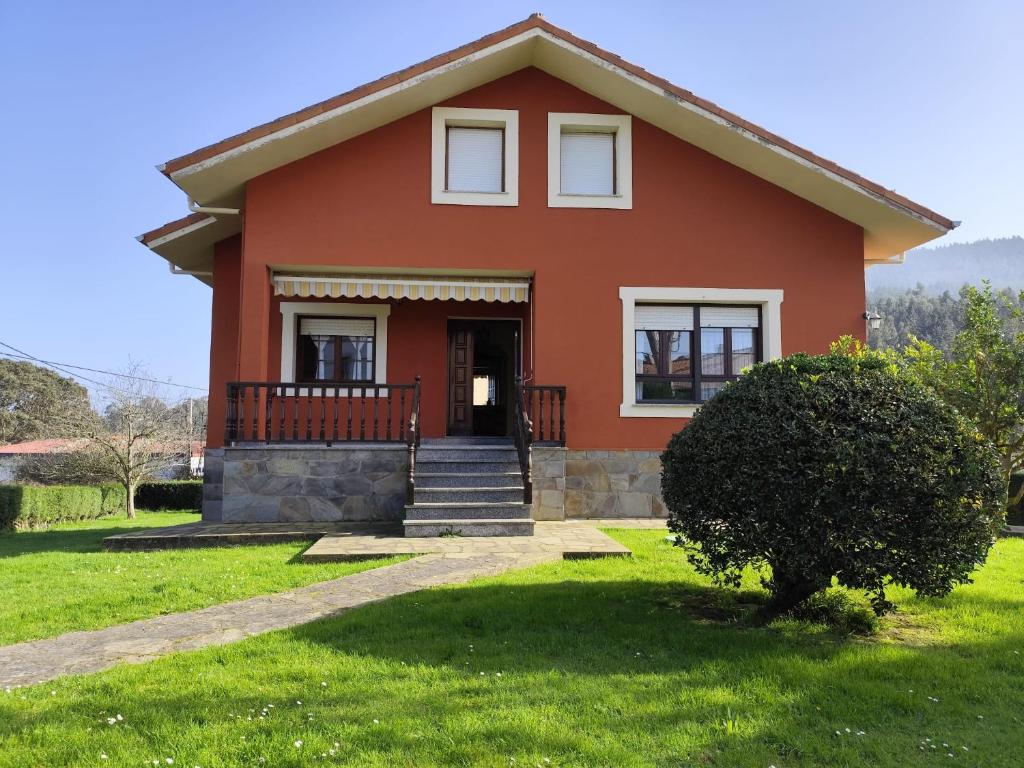 a small red house with a grass yard at El Tayo in Cudillero