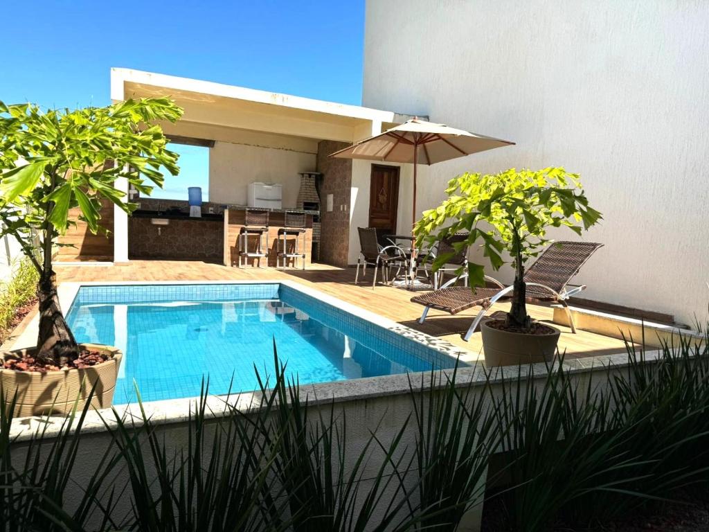 a swimming pool with two potted trees and an umbrella at Apartamento Tulum in Barra Grande