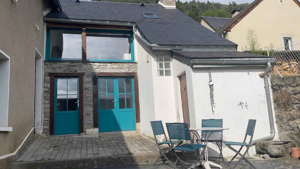 une maison avec des portes bleues, une table et des chaises dans l'établissement Le Gypaète, à Gouaux
