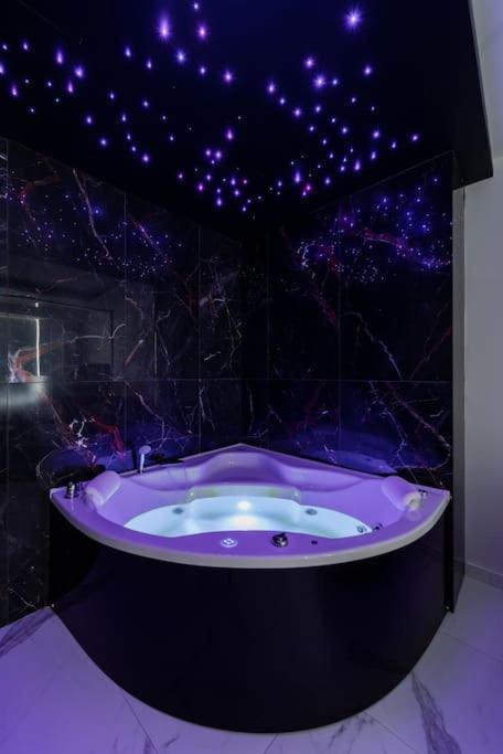 a bathroom with a tub with purple lights on the ceiling at Zebrano Spa in Novi Beograd