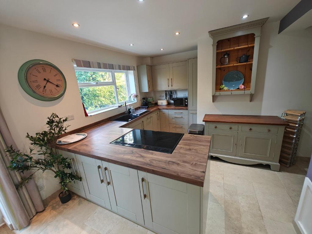 King Arthur's Rest House, Hot Tub & Garden Sleeps 10 في South Cadbury: مطبخ مع حوض وساعة على الحائط