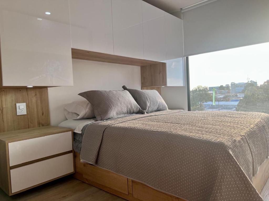 a bedroom with a bed and a large window at DF Acogedor Loft con Gym D02 in Bogotá
