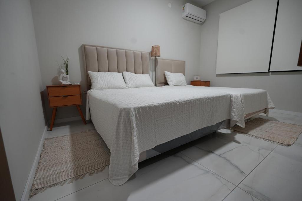 ein weißes Schlafzimmer mit einem Bett und einem Nachttisch in der Unterkunft Little House Para 3 Personas - Casa compartida in Santa Cruz de la Sierra