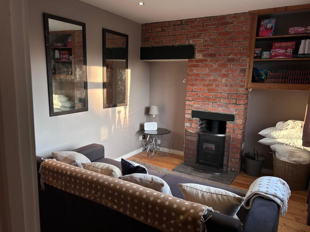 a living room with a couch and a fireplace at King Arthur's Rest House, Hot Tub & Garden Sleeps 10 in South Cadbury