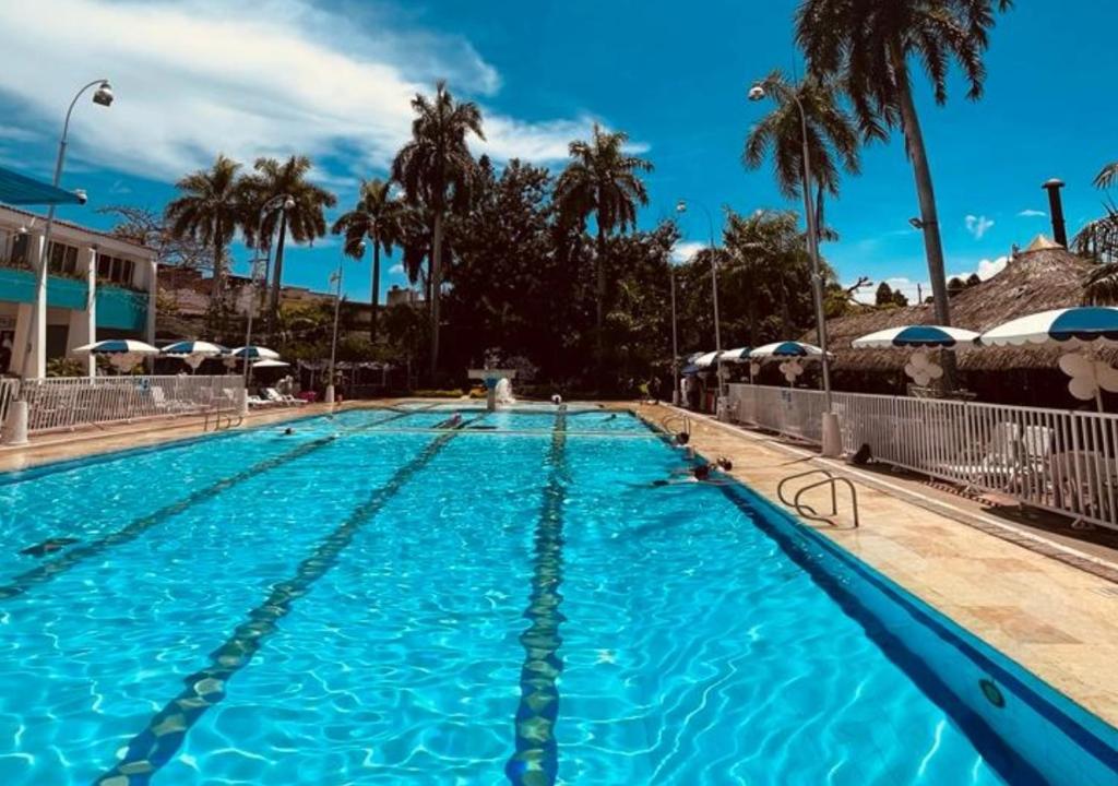 a large swimming pool with palm trees and a blue sky at Hotel Bachue Girardot in Girardot